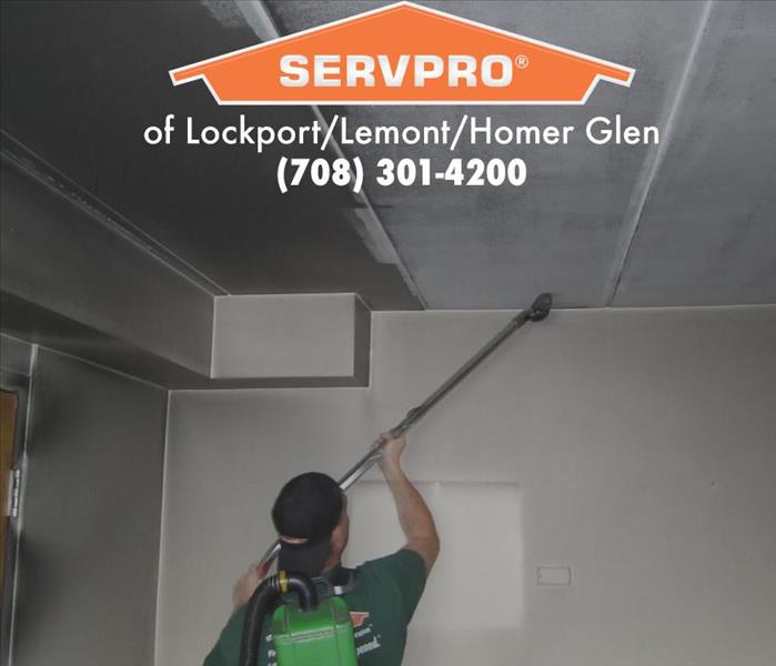 Team member in action cleaning ceiling and wall.